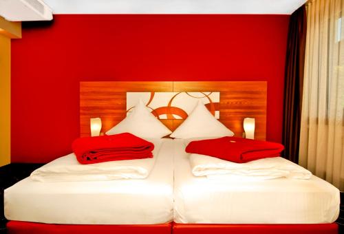 two beds in a hotel room with red pillows at Hotel Central in Nuremberg