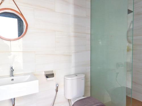 a bathroom with a toilet and a sink and a mirror at Sakanti Inn Wonosobo in Kalibeber