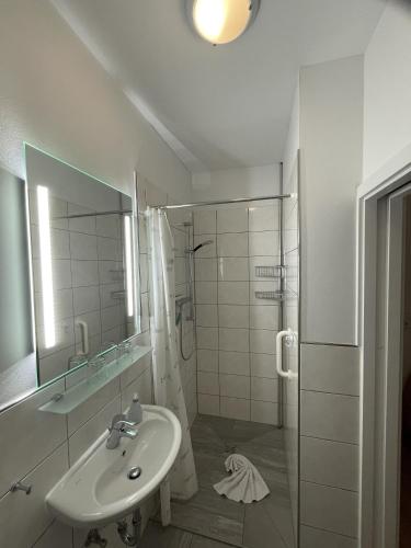 a white bathroom with a sink and a shower at Haus Breslau in Borkum