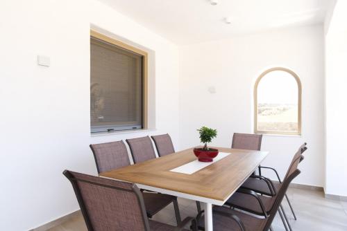 a dining room with a wooden table and chairs at Maistros Apartments Mykonos in Elia