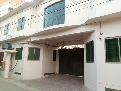 a large white building with a black garage at Hotel Business Boutique in Multan