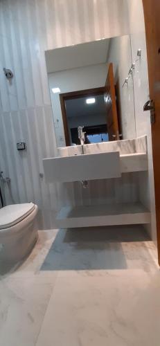 a bathroom with a sink and a toilet and a mirror at Max Suíte in Capitólio