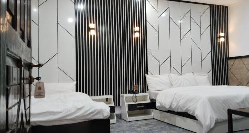 a bedroom with two beds with white sheets and black stripes at Hotel Park Way & Restaurant in Mingora
