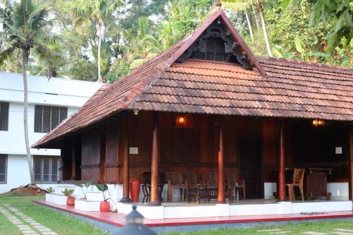 a building with a roof with tables and chairs at Poovar Heritage Homes in Pūvār