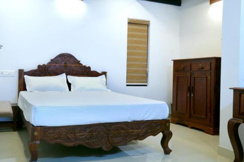 a bedroom with a bed with a wooden headboard at Poovar Heritage Homes in Pūvār