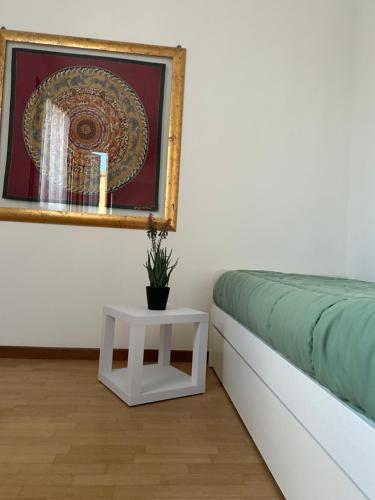 a bed with a table and a picture on the wall at Appartamento Marisa in San Vendemiano