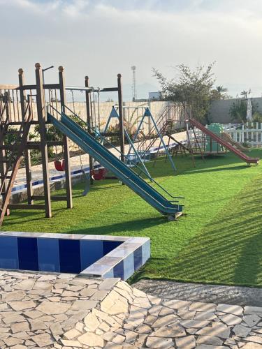 a playground with a blue slide in a park at Shinas Farm in Al Hāmilīyah