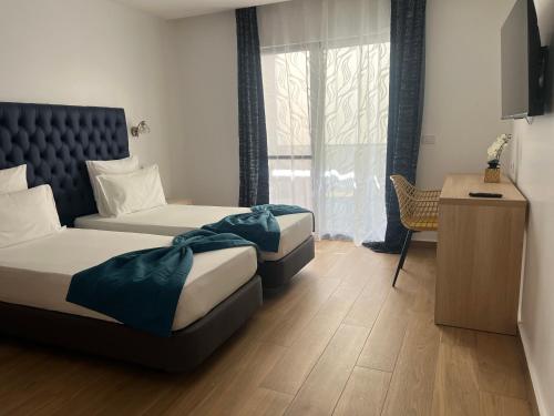 a hotel room with two beds and a desk at Hôtel Blue Sky in Tarrafal