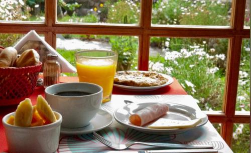 a table with a plate of food and a glass of orange juice at Amira's House Cusco in Cusco