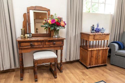 a desk with a mirror and a vase of flowers on it at Khanyeni in Himeville