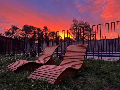 two chairs in front of a fence at sunset at Cabañas piedra roja in Pucón