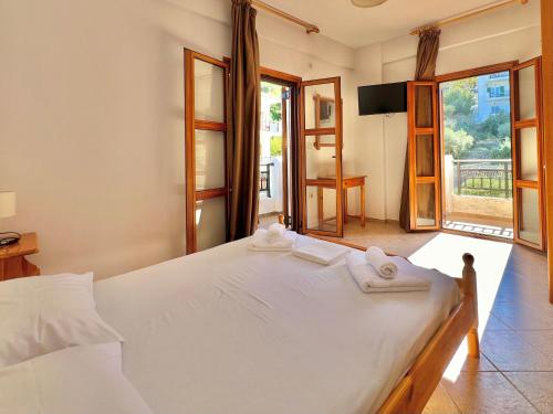 a bedroom with a white bed with towels on it at Marinos Studios and Apartments in Gialiskari