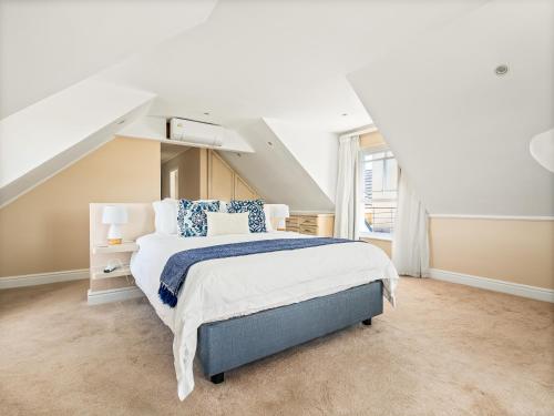 a white bedroom with a large bed with blue pillows at Chandler Heights in Knysna