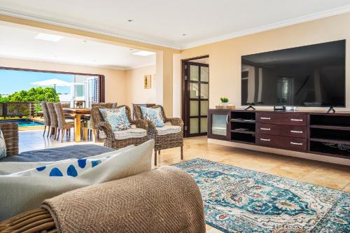 a living room with a large television and chairs at Chandler Heights in Knysna