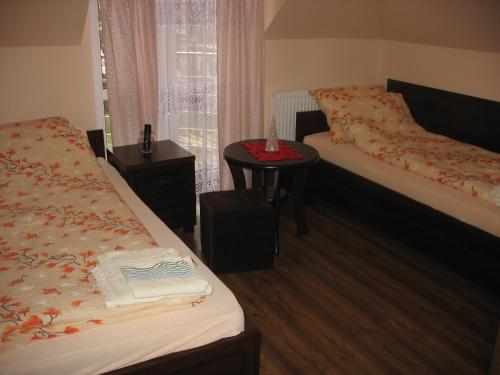Cette chambre comprend deux lits et une table avec une fenêtre. dans l'établissement Willa Viola, à Busko-Zdrój