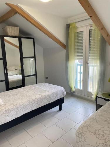 une chambre avec deux lits et une grande fenêtre dans l'établissement Appartement T3 lumineux très bien équipé avec balcon, à Salies-de-Béarn