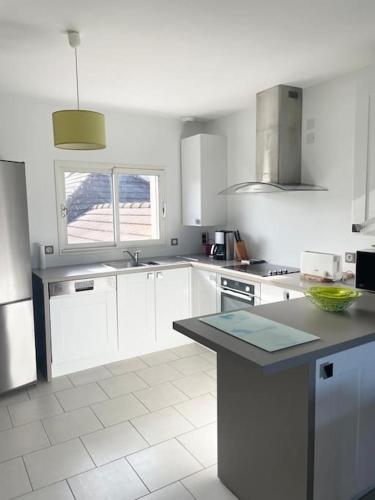 une cuisine avec des armoires blanches et un comptoir dans l'établissement Appartement T3 lumineux très bien équipé avec balcon, à Salies-de-Béarn