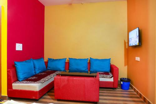 a living room with a red couch and blue pillows at Chithralaya Guest House in Yercaud
