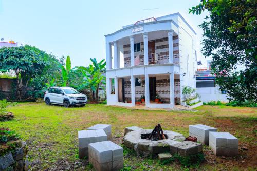 a car parked in front of a white building at Chithralaya Guest House in Yercaud