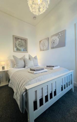 a white bedroom with a white bed with a chandelier at Cosy Cottage in Stirling