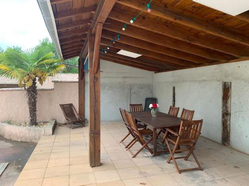 a wooden table and chairs on a patio at Maison familiale avec piscine proche Périgueux in Chancelade