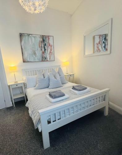 a white bed in a room with two tables at Cosy Cottage in Stirling
