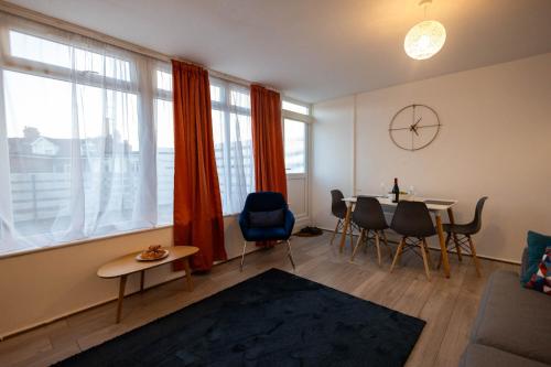 a living room with a table and chairs and windows at Entire 3 Bedroom Apartment in Felixstowe in Felixstowe