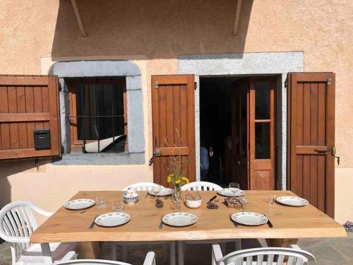 une table en bois avec des chaises blanches et un tableasteryasteryasteryasteryasteryasteryastery astery astery dans l'établissement Maison de village avec jardin, à Saint Firmin