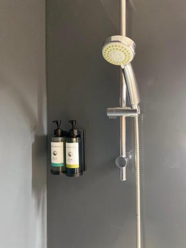 une pomme de douche et deux bouteilles sur un mur dans l'établissement Le Girouard - City Center - Private Parking - WIFI, NETFLIX, à Poitiers