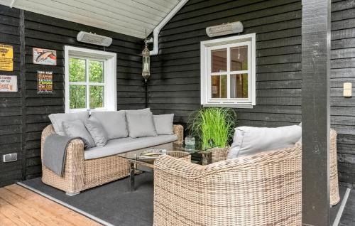 a patio with wicker furniture and a glass table at 3 Bedroom Nice Home In Kibæk in Kibæk
