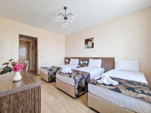 a hotel room with three beds and a vase of flowers at Айляк Клуб Хисаря - Бутиков Хотел&СПА с Elegant Ultra All Inclusive in Hisarya
