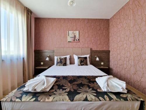 a bedroom with a large bed with pink wallpaper at Айляк Клуб Хисаря - Бутиков Хотел&СПА с Elegant Ultra All Inclusive in Hisarya