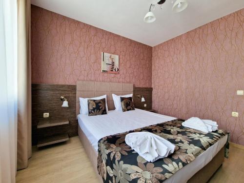 a bedroom with a bed and a pink wall at Айляк Клуб Хисаря - Бутиков Хотел&СПА с Elegant Ultra All Inclusive in Hisarya