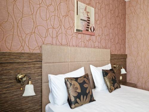 a bedroom with a bed with white pillows and pink wallpaper at Айляк Клуб Хисаря - Бутиков Хотел&СПА с Elegant Ultra All Inclusive in Hisarya