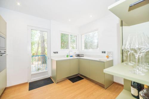 - une cuisine avec des comptoirs blancs et 2 fenêtres dans l'établissement La Villa les Pins, à Saint-Georges-de-Didonne