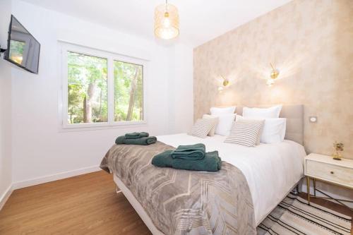 - une chambre avec un grand lit et 2 serviettes vertes dans l'établissement La Villa les Pins, à Saint-Georges-de-Didonne