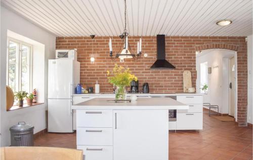 a kitchen with white cabinets and a brick wall at Cozy Home In Gärsnäs With Wifi in Gärsnäs