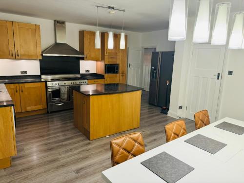 a large kitchen with wooden cabinets and a counter top at Elegant 5 Bed house Free parking Free WiFi in Shirley