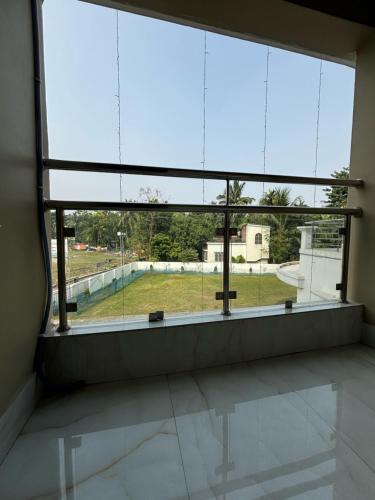 an empty room with a large window in a building at ICHHAMATI HOTEL AND RESTAURANT in Hāsnābād