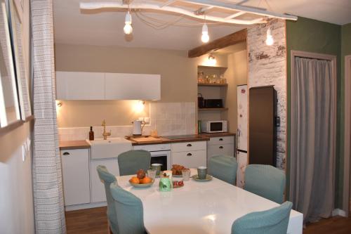 une cuisine avec une table blanche et des chaises bleues dans l'établissement Yvonnette Cottage, à Salles-Courbatiès