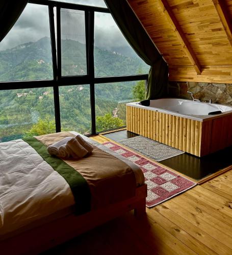 a bedroom with a bed and a tub in a window at Alfa Dağevleri in Rize