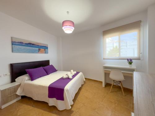 a bedroom with a bed with purple pillows and a desk at Apartamento El Barco 1 linea PLAYA, PARKING, WIFI in Torrox Costa
