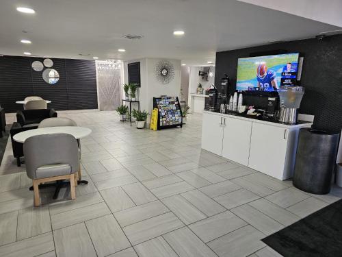 a waiting room with a table and a tv on a wall at La Quinta I-95 Deerfield Beach - Next to The Home Depot & Behind The Wawa in Deerfield Beach
