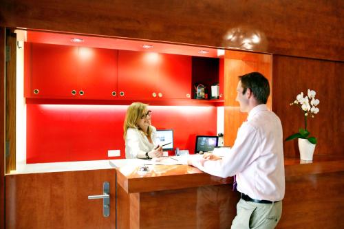a man and a woman standing at a desk at Hotel De la Paix in Luzern