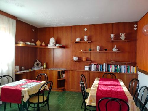 a dining room with a table and chairs and bookshelves at Hotel Veles in Querciola