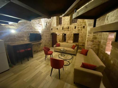 a living room with a couch and chairs and a tv at Nina s House Charming Loft in 700-Year-Old Gem in heart of Byblos in Jbeil