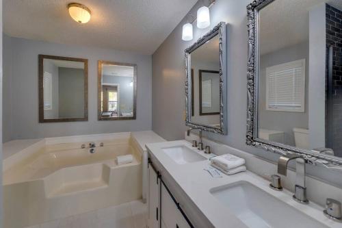 a bathroom with two sinks and a tub and two mirrors at Oasis by JSU and McLellan Yahou Lake in Anniston
