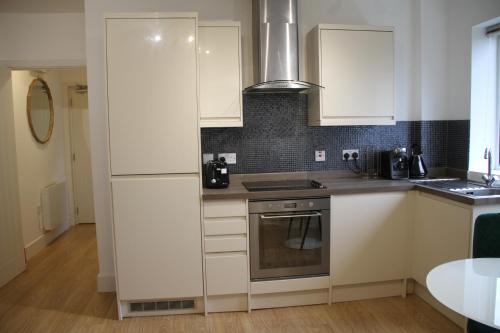 a kitchen with white cabinets and a stove at No 13 Colchester Town Flat with Kitchen & Parking in Colchester