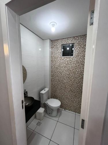a bathroom with a toilet and a television on the wall at Casa a 1 km andando até a praia, barra sul de Balneário Camboriú in Balneário Camboriú