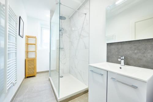 une salle de bain blanche avec une douche et un lavabo dans l'établissement BE-1 - Appartement F4 pour 1-6 pers 1er étage au centre de Mulhouse, à Mulhouse